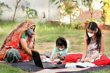 photograph of Indian mother and children doing schoolwork outside during Covid-19