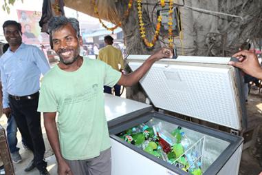 Photo of smiling man next to solar fridge in India