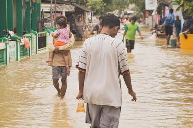 Photograph of people in Malaysia wading down a heavily flooded street