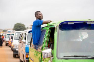 Image of African man, sitting on a car window, cars in traffic jam- transportation concept