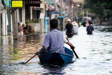 Image of two men in a boat navigating a flooded street after a typhoon