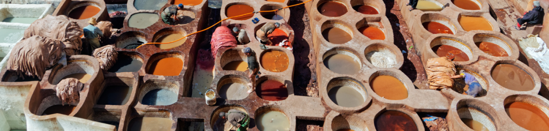 Photo of clay pots from above. The pots are filled with brightly coloured substances