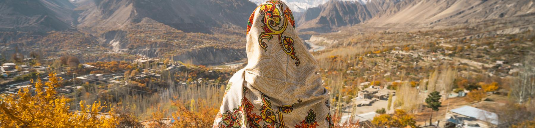 Photo of a woman with her back to the camera looking out over the mountains in Pakistan